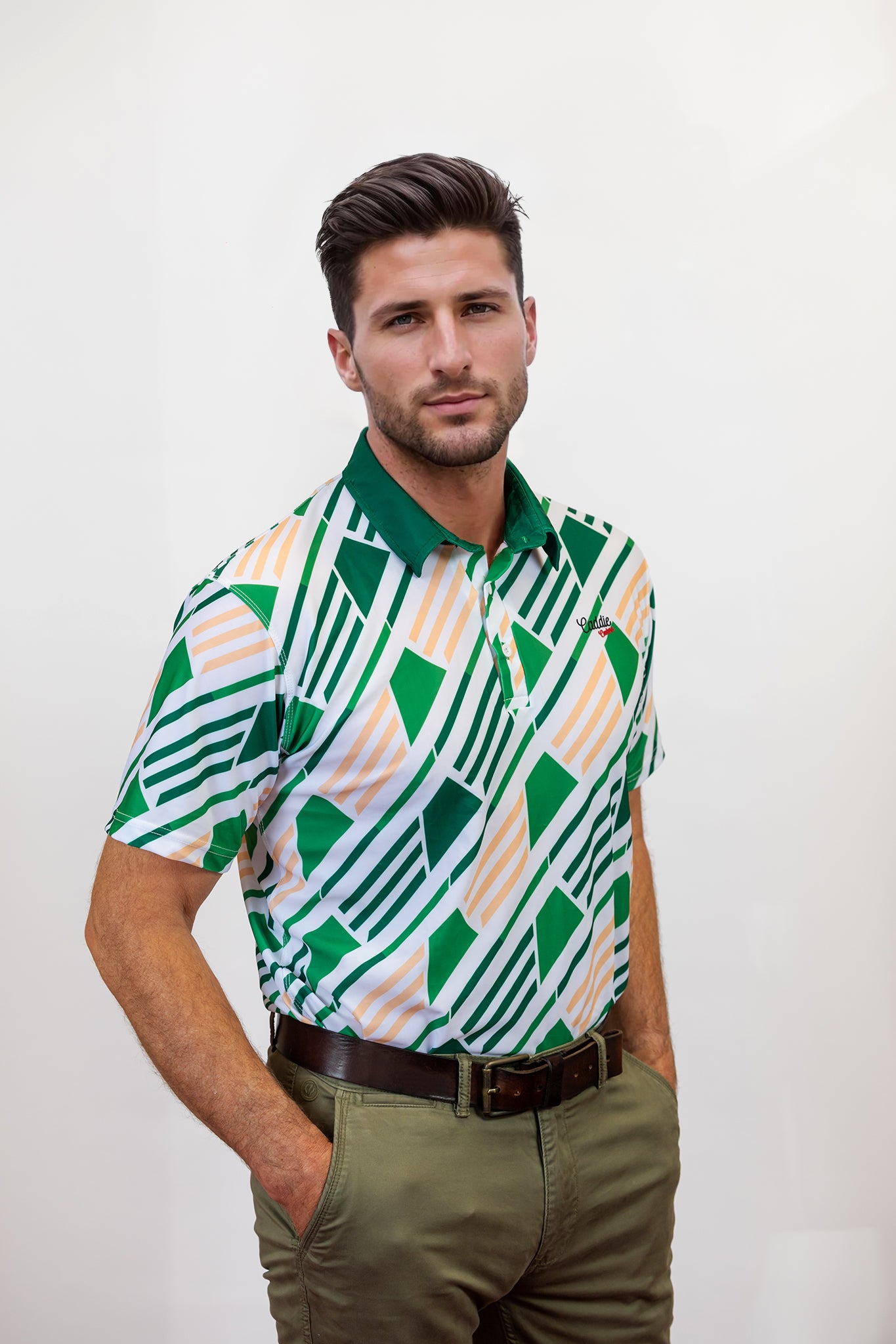 Man wearing a patterned golf shirt with green and white geometric design against a plain background