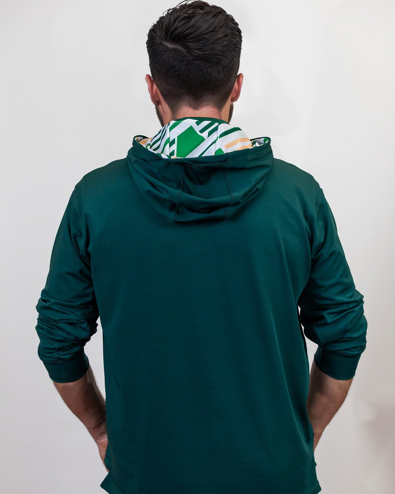 Person wearing a green golf hoodie with a patterned hood against a white background