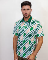 Man wearing a patterned golf shirt with green and white geometric design on a plain background