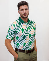 Man wearing a patterned golf shirt with green and white geometric design against a plain background