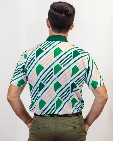 Man wearing a patterned golf shirt with green, white design on a plain background