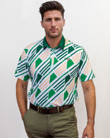 Man wearing a patterned golf shirt and green pants against a white background