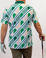 Person wearing a green and white patterned shirt holding a golf club.