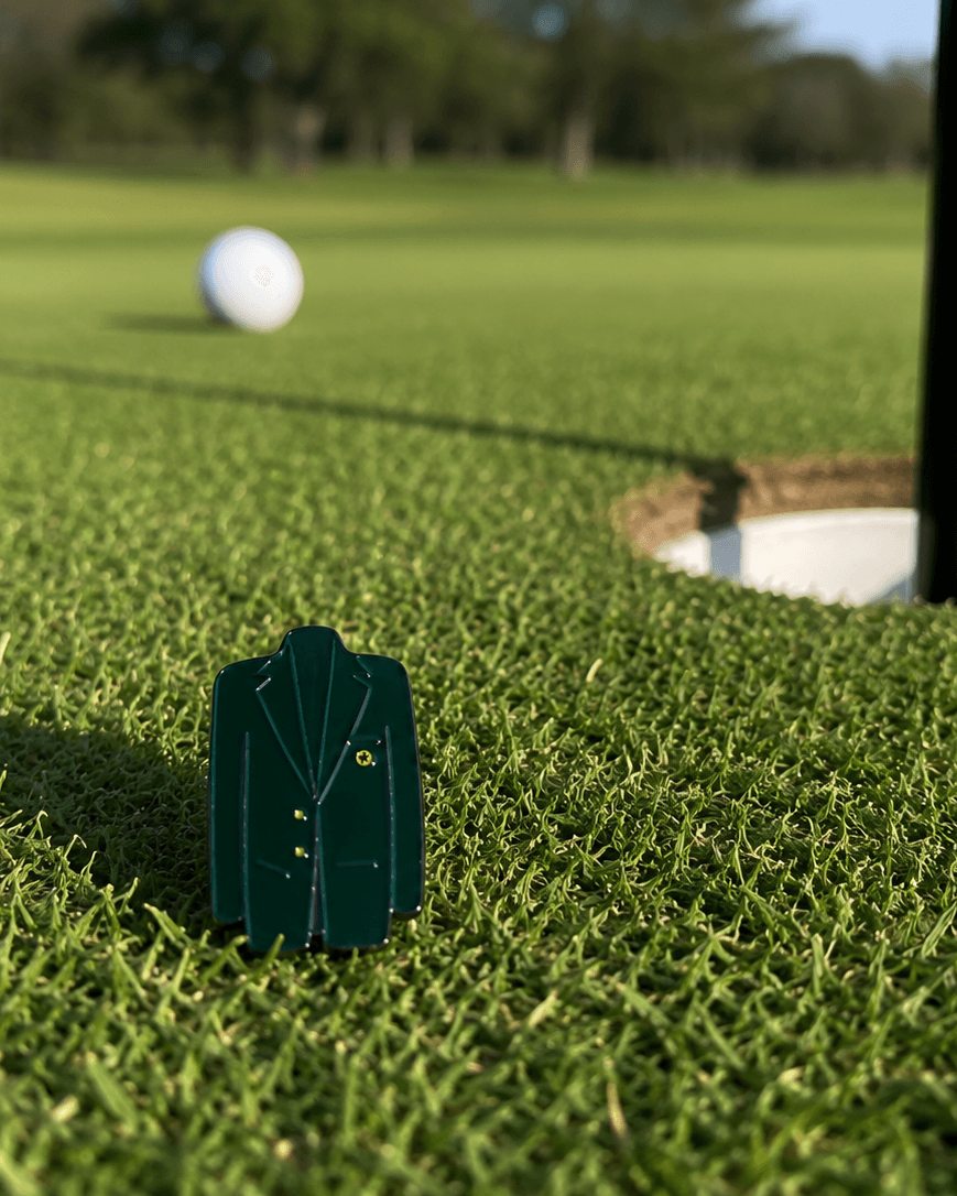 Golf ball and green jacket marker on a golf course with a hole in the background