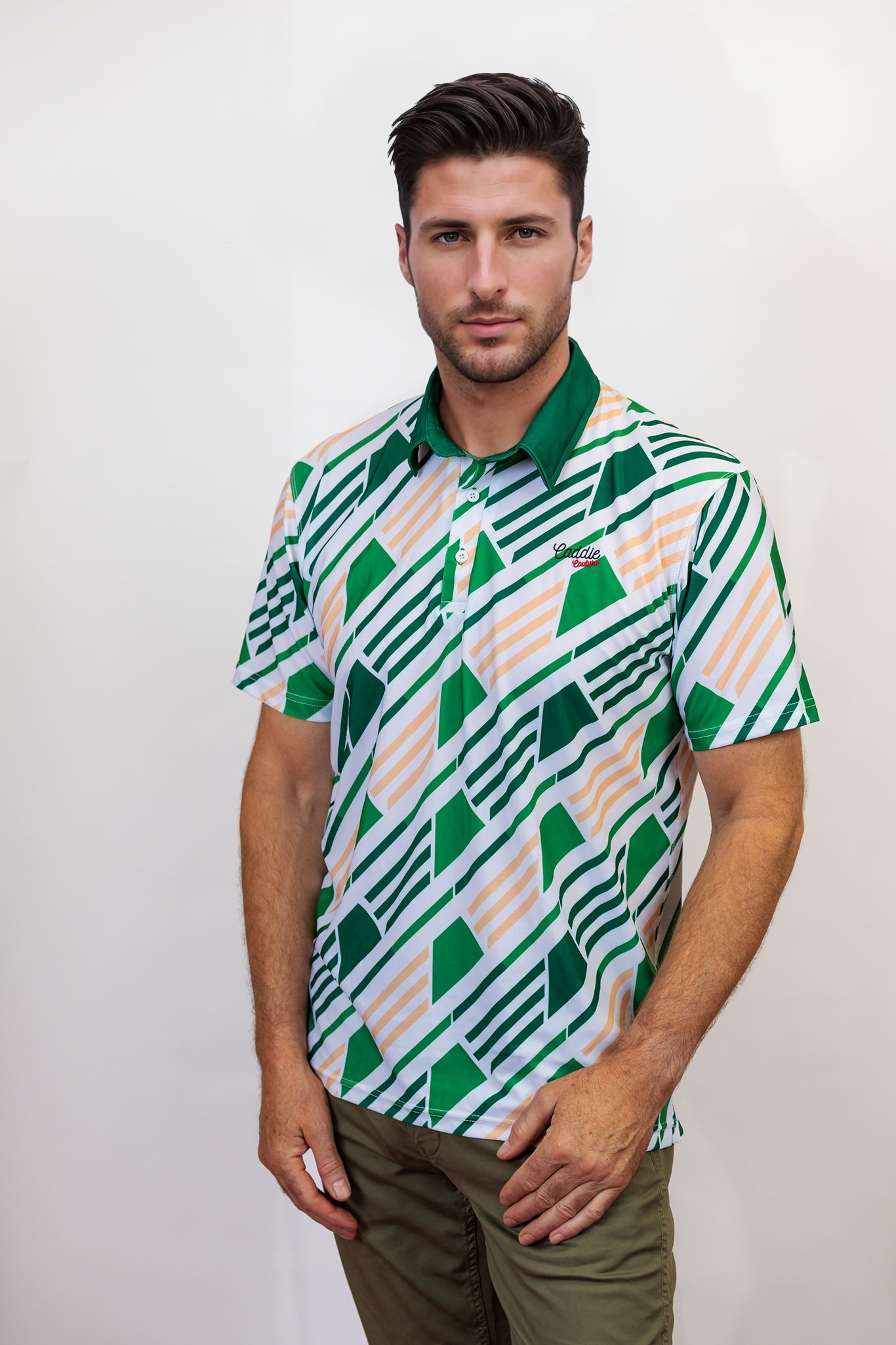Man wearing a patterned golf shirt with green and white geometric design on a plain background