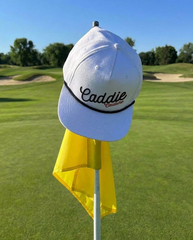 White cap with 'Caddie' text on a golf flagstick with a golf course background