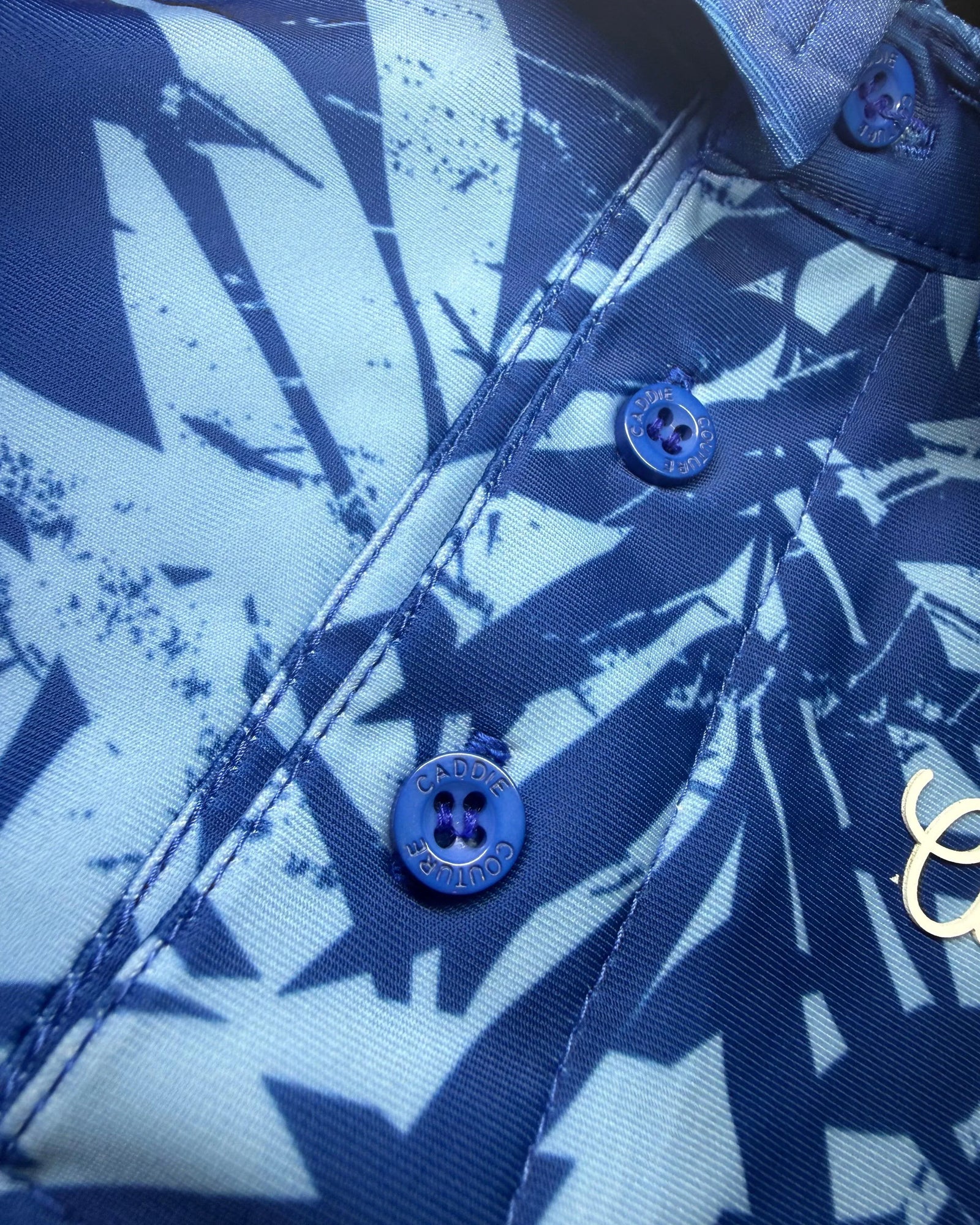 Close-up of Atlantic Palm polo palm print, branded buttons and Caddie Couture logo