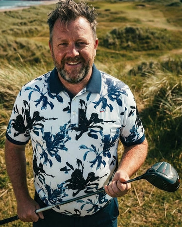 Man holding a golf club in a grassy outdoor setting