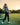 Young girl practicing golf on a driving range with trees and sunset in the background