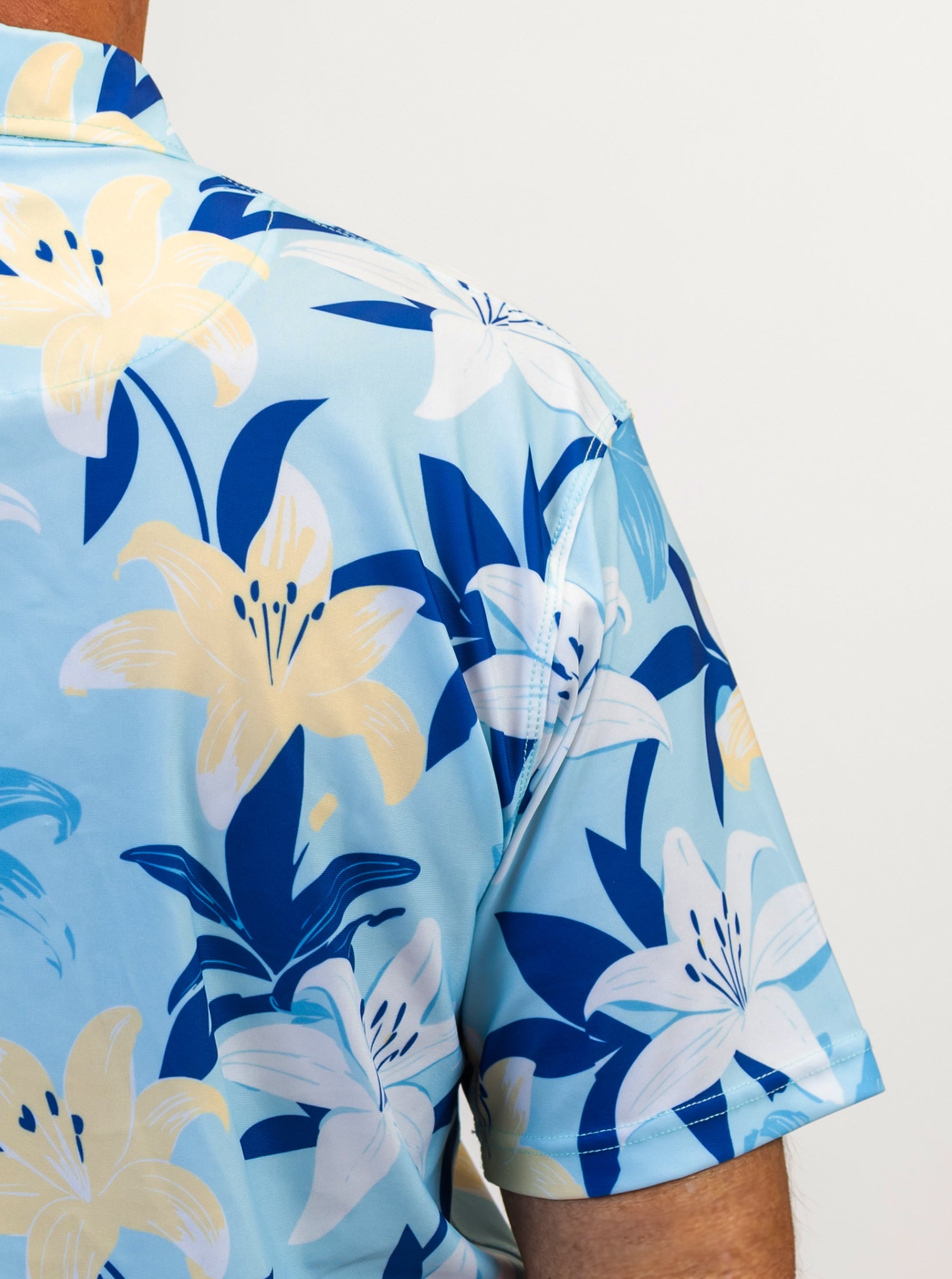 Golf shirt with blue and yellow floral pattern on a light blue background