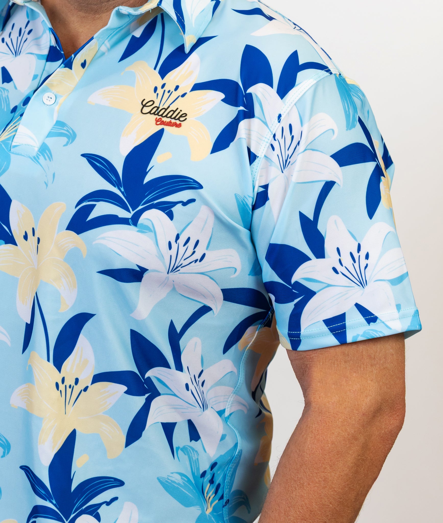 Blue floral patterned golf shirt with 'Caddie couture' branding on a plain background