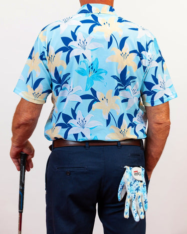 Person wearing a blue floral golf shirt and holding a golf glove with a brand logo caddie couture.
