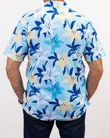 Person wearing a blue floral patterned golf shirt on a plain background