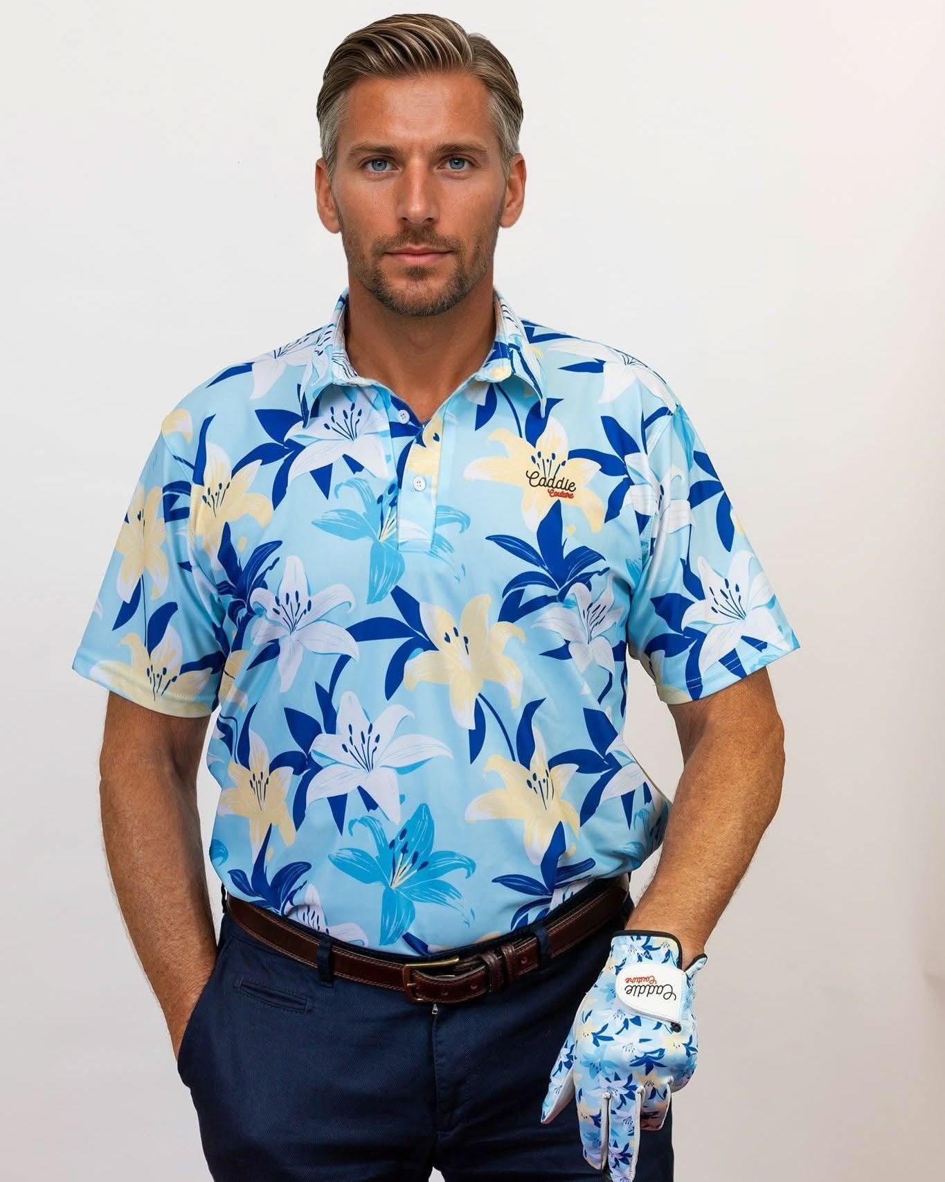 Man wearing a blue floral golf shirt and dark pants, holding a golf club with a white background