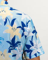 Golf shirt with blue and yellow floral pattern on a light blue background