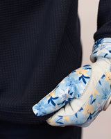 Person wearing a blue floral glove on a neutral background