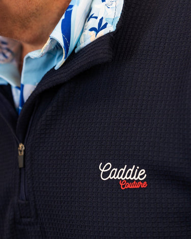 Navy blue jacket with 'Caddie Couture' logo, featuring a floral patterned shirt underneath.