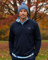 Man wearing a navy blue caddie couture Qzip, standing in an autumn park.