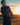Man holding a golf club with a sunset in the background