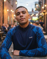 Man wearing a blue jacket with a brand logo in an outdoor setting