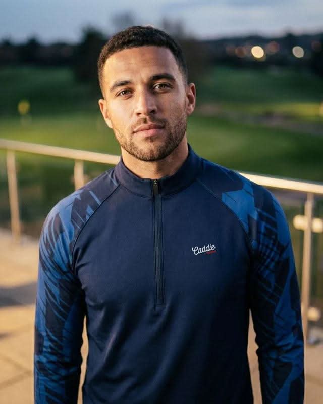 Man wearing a blue athletic jacket with a golf course in the background