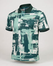A short-sleeve polo shirt with a green, teal, and white abstract brushstroke pattern, featuring a dark green collar and sleeve cuffs, displayed on a neutral light gray background.