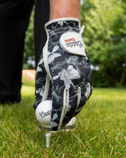 Golf glove and ball on a tee with a blurred green background