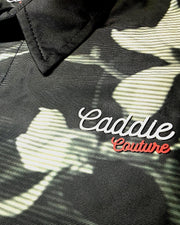 Black camouflage jacket with 'Caddie Couture' logo on a dark background