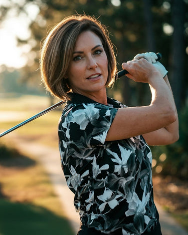 Woman playing golf on a course with trees in the background