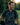 Man laughing outdoors with a blurred natural background