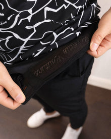 Person holding a black and white patterned bag with visible branding.