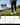 Person wearing black joggers and white shoes on a golf course with a size guide overlay.