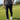 Person wearing a black and white patterned shirt, black pants, and white shoes on a golf course.