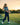 Young girl practicing golf on a driving range with trees and sunset in the background