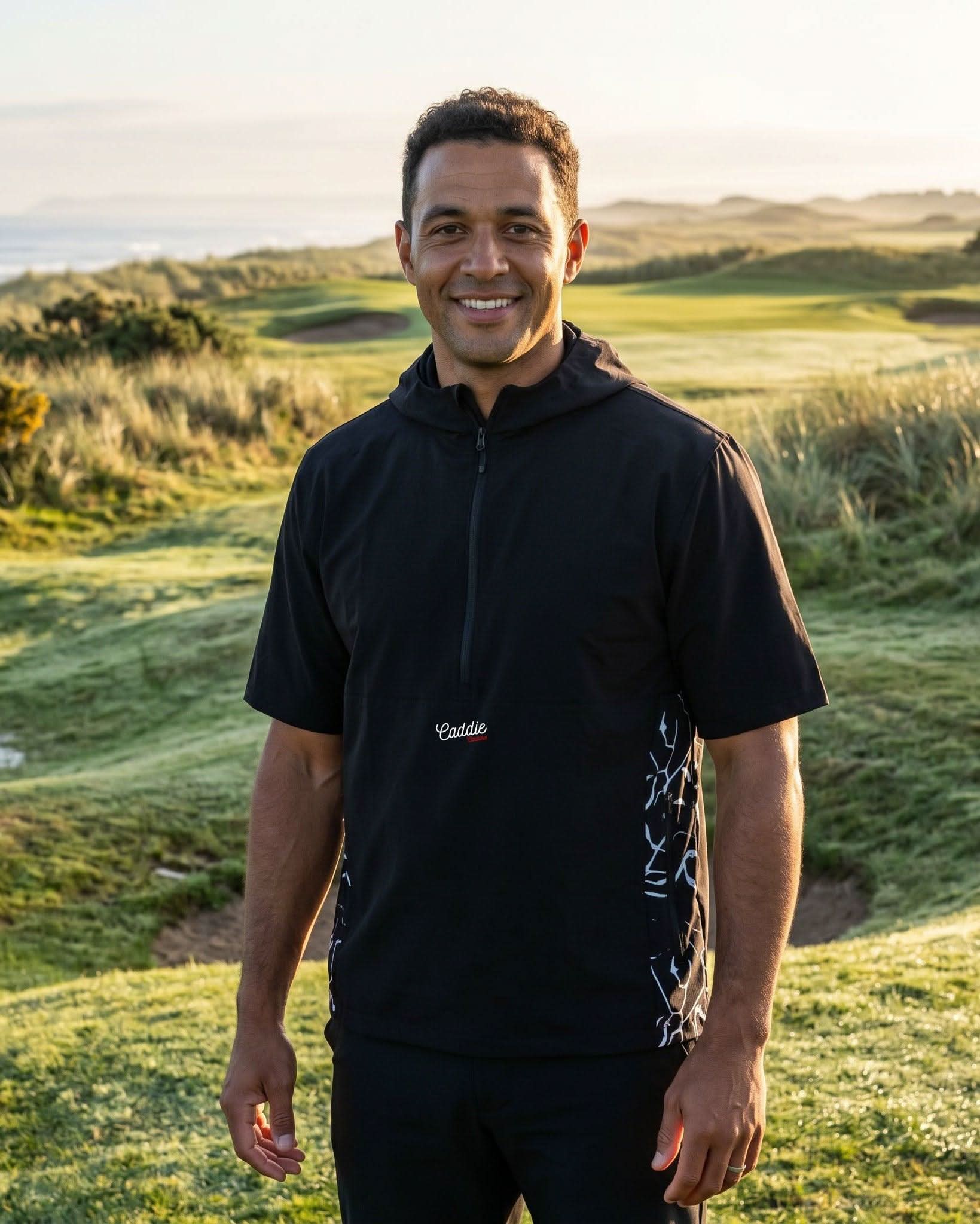 Man in black hoodie standing on a golf course with scenic background