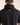 Person wearing a black shirt with 'Caddie' branding on the back against a beige background