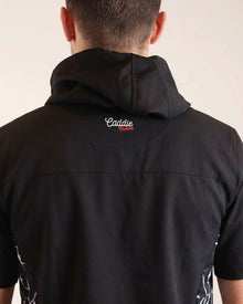 Person wearing a black shirt with 'Caddie' branding on the back against a beige background