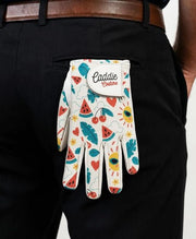 Colorful patterned glove with 'Caddie Couture' label held in front of black pants.