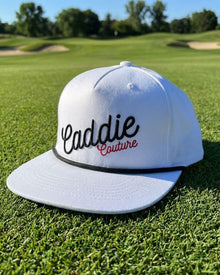 White cap with 'Caddie Couture' text on a golf course