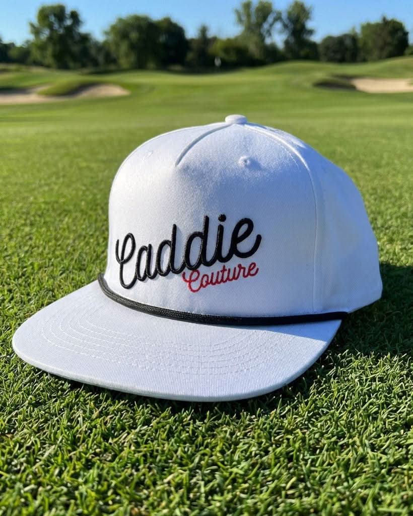 White cap with 'Caddie Couture' text on a golf course