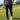 Person wearing a black and white patterned shirt, black pants, and white shoes on a golf course.