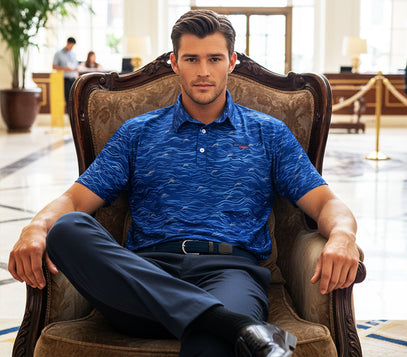 man sitting in large chair with legs crossed wearing blue waves golf polo