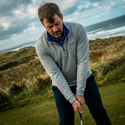 Man playing golf on a coastal course with ocean in the background