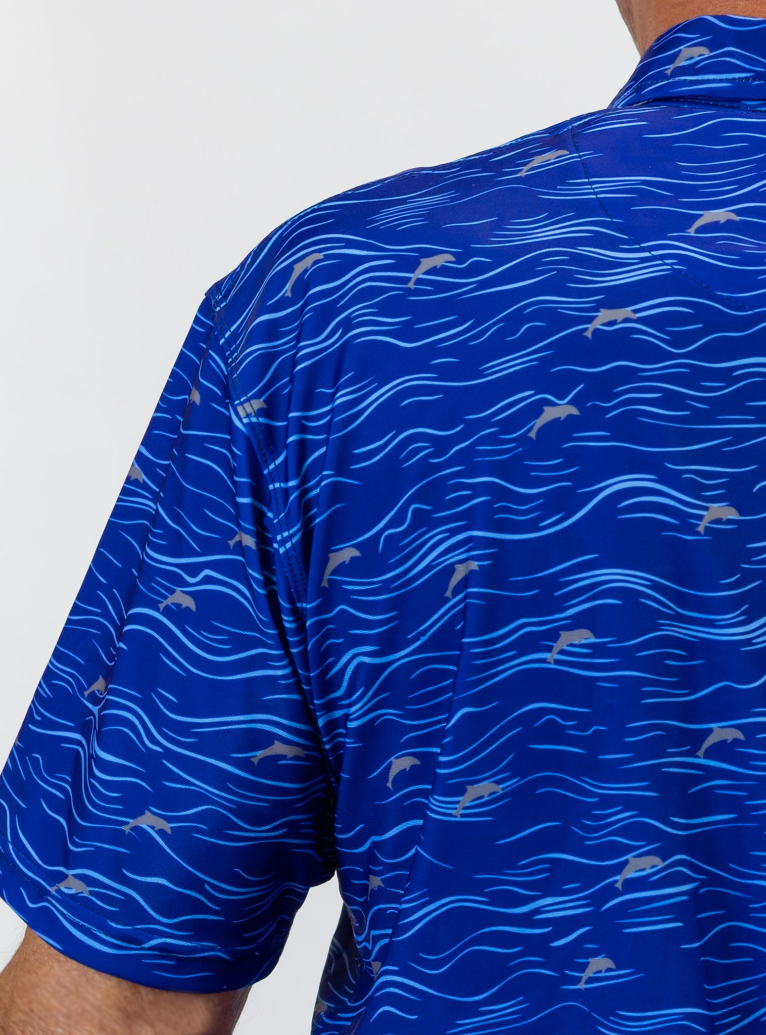 Blue golf shirt with dolphin pattern on a white background