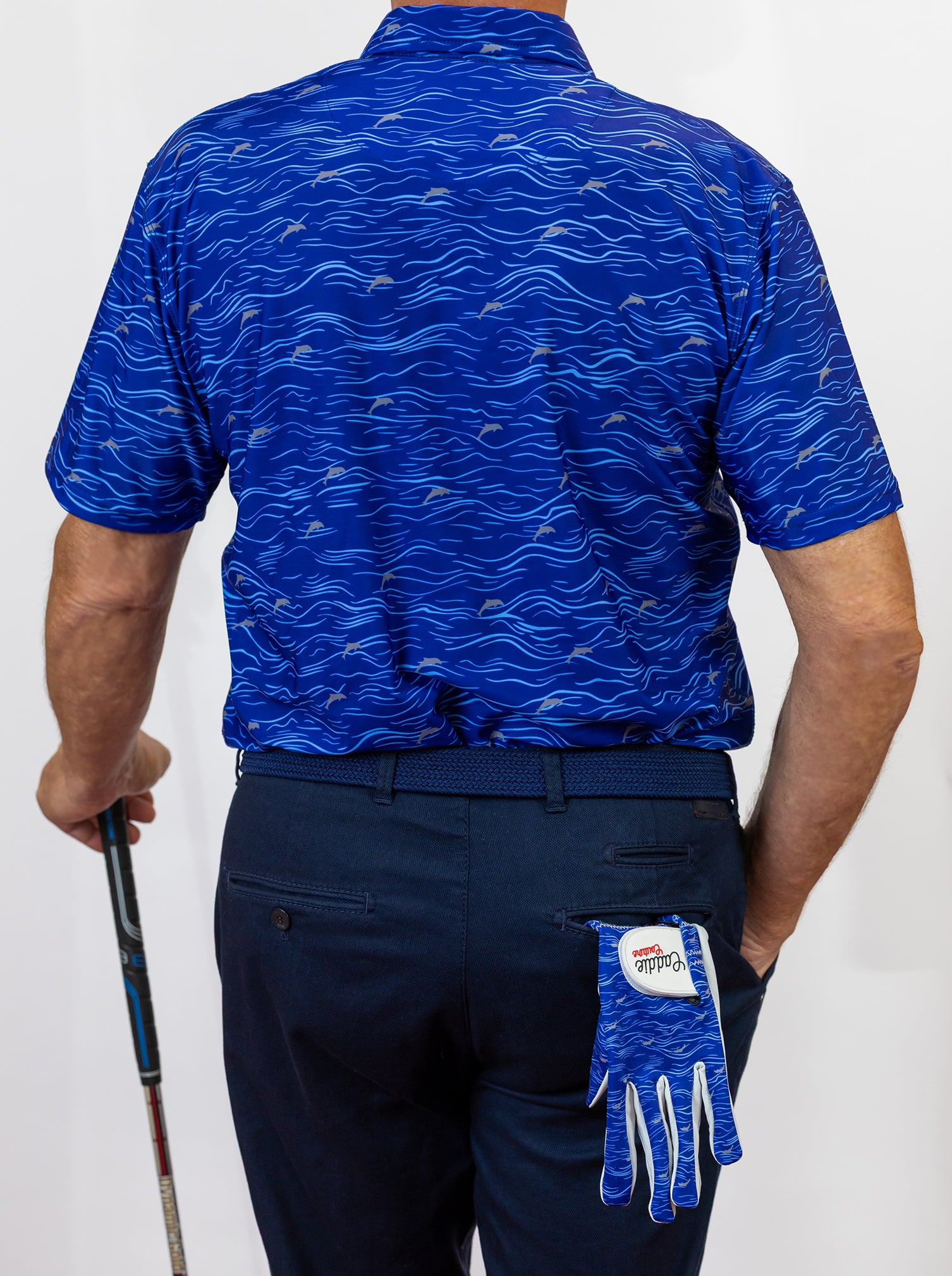 Person wearing a blue patterned golf shirt and navy pants, holding a golf club, with a blue glove on a white background.