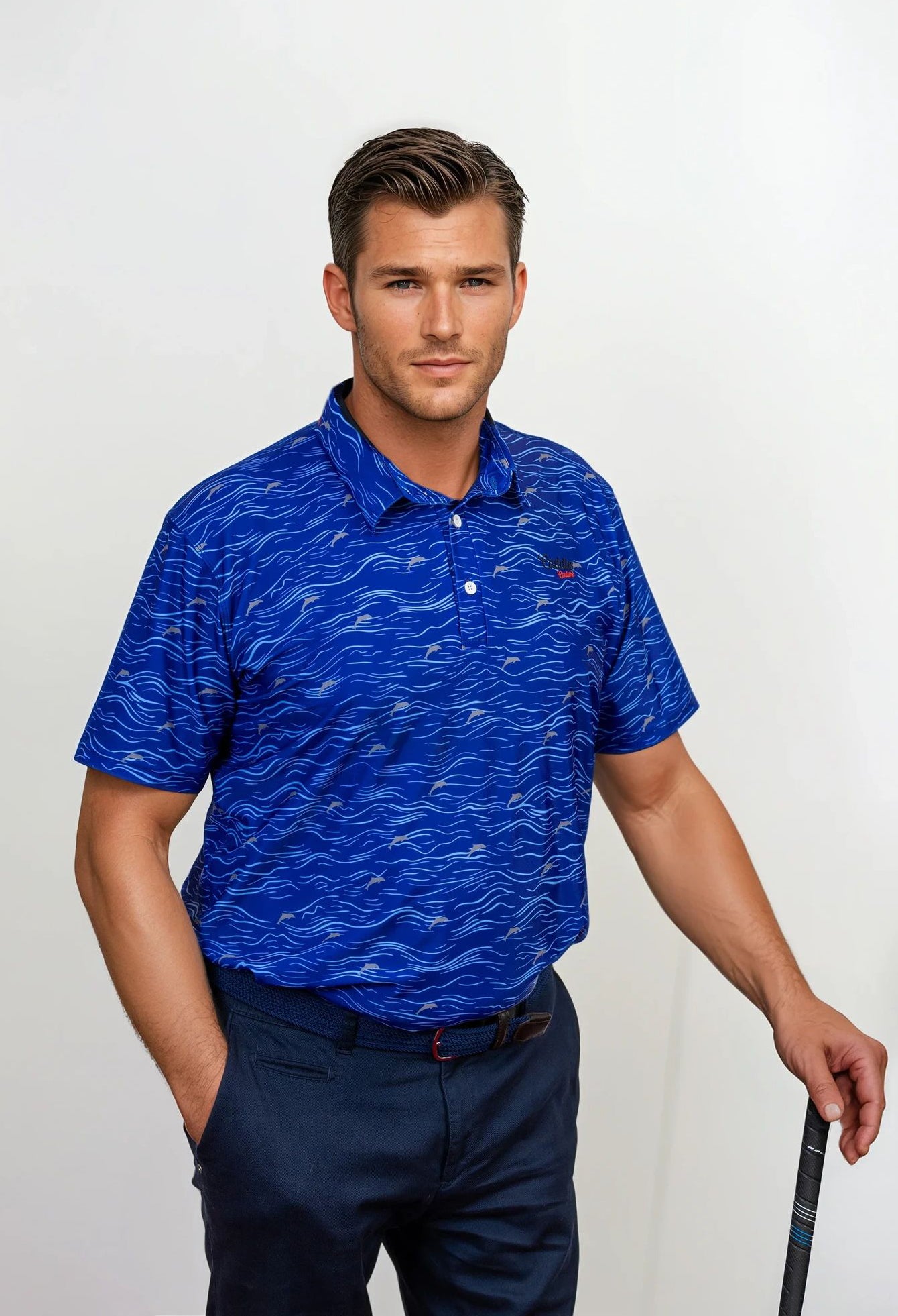 Man wearing a blue patterned golf polo shirt and dark pants, holding a golf club.