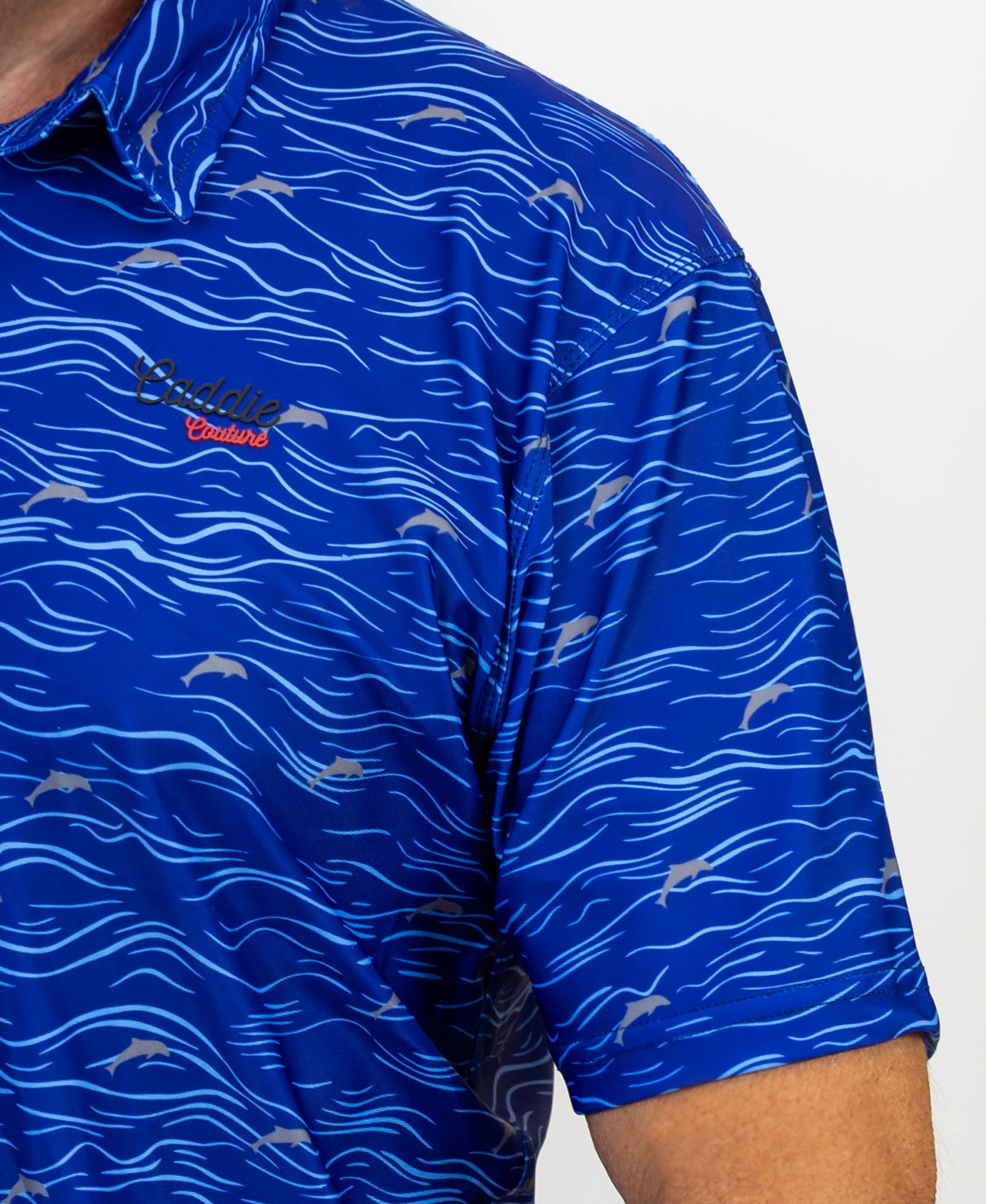 Blue patterned Golf shirt with a Caddie Couture logo on a grey background