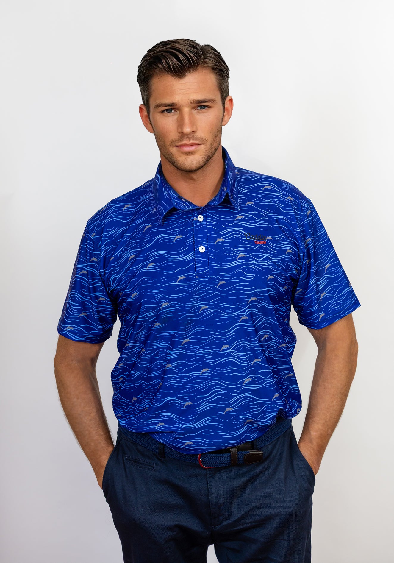 Man wearing a blue patterned golf polo shirt with a visible caddie couture logo on a white background