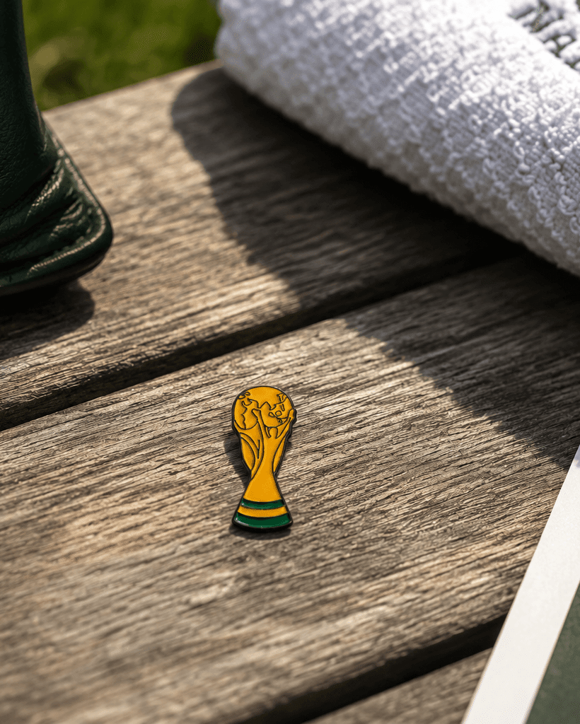 Small trophy-shaped object on a wooden surface with Augusta National Golf Club hat in the background